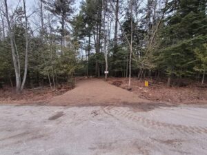 Gravel driveway into wooded lot off paved road