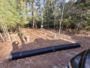 Preparation work for new gravel driveway into woods with plastic drain pipe