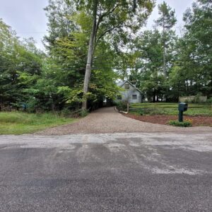 Gravel driveway refresh in front of home with split rail fence and mailbox