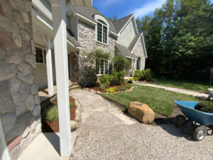 Landscaping with boulders, mulched flower beds with cobble edging, flagstone walkway and sod being installed