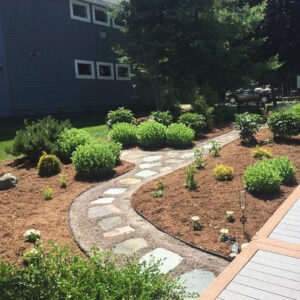 Rustic flagstone and gravel walkway with edging and landscaped flower beds on side of home