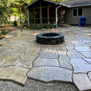 Flagstone patio being installed with stone fire pit in backyard